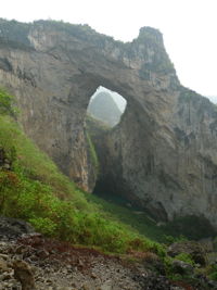 Dans la paroi est de l'énorme effondrement (un Tiankeng de pente dégénéré) de 200 m de diamètre, un gros porche perché forme un pont-naturel. Il domine plan d'eau regard sur la rivière souterraine. Grotte de Dajing dong Qun 大井洞. (Dajing 大井, Qiannan 黔南, Luodian罗甸, Guizhou 贵州省, Chine)