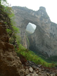 Dans la paroi est de l'énorme effondrement (un Tiankeng de pente dégénéré) de 200 m de diamètre, un gros porche perché forme un pont-naturel. Il domine plan d'eau regard sur la rivière souterraine. Grotte de Dajing dong Qun 大井洞. (Dajing 大井, Qiannan 黔南, Luodian罗甸, Guizhou 贵州省, Chine)