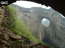 Dans la paroi est de l'énorme effondrement (un Tiankeng de pente dégénéré) de 200 m de diamètre, un gros porche perché forme un pont-naturel. Il domine plan d'eau regard sur la rivière souterraine. Grotte de Dajing dong Qun 大井洞. (Dajing 大井, Qiannan 黔南, Luodian罗甸, Guizhou 贵州省, Chine)