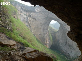 Dans la paroi est de l'énorme effondrement (un Tiankeng de pente dégénéré) de 200 m de diamètre, un gros porche perché forme un pont-naturel (vu depuis une des grottes abri de la paroi ouest) Grotte de Dajing dong Qun 大井洞. (Dajing 大井, Qiannan 黔南, Luodian罗甸, Guizhou 贵州省, Chine)