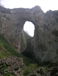 Dans la paroi est de l'énorme effondrement (un Tiankeng de pente dégénéré) de 200 m de diamètre, un gros porche perché forme un pont-naturel. Il domine plan d'eau regard sur la rivière souterraine. Grotte de Dajing dong Qun 大井洞. (Dajing 大井, Qiannan 黔南, Luodian罗甸, Guizhou 贵州省, Chine)