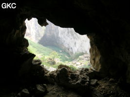 Dans l'énorme effondrement (un Tiankeng de pente dégénéré) de 200 m de diamètre. Vu d'une des grottes abri de la paroi ouest : le plan d'eau regard sur la rivière souterraine, occupe le coin est. Grotte de Dajing dong Qun 大井洞. (Dajing 大井, Qiannan 黔南, Luodian罗甸, Guizhou 贵州省, Chine)