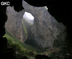 Dans la paroi est de l'énorme effondrement (un Tiankeng de pente dégénéré) de 200 m de diamètre, un gros porche perché forme un pont-naturel. Il domine plan d'eau regard sur la rivière souterraine. Grotte de Dajing dong Qun 大井洞. (Dajing 大井, Qiannan 黔南, Luodian罗甸, Guizhou 贵州省, Chine)