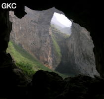 Dans la paroi est de l'énorme effondrement (un Tiankeng de pente dégénéré) de 200 m de diamètre, un gros porche perché forme un pont-naturel. Il domine plan d'eau regard sur la rivière souterraine. Grotte de Dajing dong Qun 大井洞. (Dajing 大井, Qiannan 黔南, Luodian罗甸, Guizhou 贵州省, Chine)