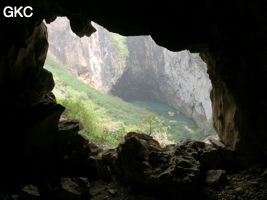 Dans l'énorme effondrement (un Tiankeng de pente dégénéré) de 200 m de diamètre. Vu d'une des grottes abri de la paroi ouest : le plan d'eau regard sur la rivière souterraine, occupe le coin est. Grotte de Dajing dong Qun 大井洞. (Dajing 大井, Qiannan 黔南, Luodian罗甸, Guizhou 贵州省, Chine)