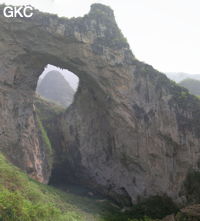 Dans la paroi est de l'énorme effondrement (un Tiankeng de pente dégénéré) de 200 m de diamètre, un gros porche perché forme un pont-naturel. Il domine plan d'eau regard sur la rivière souterraine. Grotte de Dajing dong Qun 大井洞. (Dajing 大井, Qiannan 黔南, Luodian罗甸, Guizhou 贵州省, Chine)