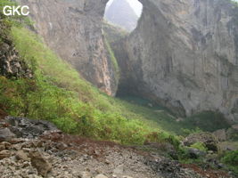 Dans la paroi est de l'énorme effondrement (un Tiankeng de pente dégénéré) de 200 m de diamètre, un gros porche perché forme un pont-naturel. Il domine plan d'eau regard sur la rivière souterraine. Grotte de Dajing dong Qun 大井洞. (Dajing 大井, Qiannan 黔南, Luodian罗甸, Guizhou 贵州省, Chine)