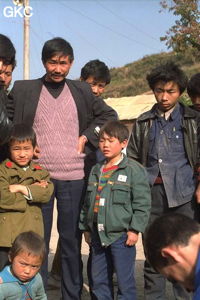 Sur la place près de la grotte de Jiutiandong, Cyriaque est en train de casser son carbure sous des regards curieux. (Sangzhi, Hunan)