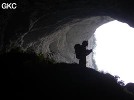 Topographe en contre jour dans l'entrée de la grotte de Laoyingwodong - 老鹰窝洞 (Santang 三塘, Zhijin 织金, Bijie Diqu 毕节地区, Guizhou 贵州省, Chine)