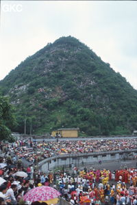 Le piton dominant le stade se transforme en tribune pour la grande fête de célébration du retour de Hong Kong à la Chine. Une foule à faire pâlir les commissions de sécurité les plus laxistes, les couleurs vives des costumes d'une multitude de figurants contrastent avec la grisaille des bâtiments alentours. Et le tout pour un spectacle de deux heures ou se côtoient le pire et le meilleur... Stade de Liupanshui (Suicheng, Guizhou)