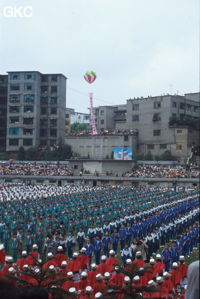 Grande fête pour célébrer le retour de Hong Kong à la Chine. Une foule à faire pâlir les commissions de sécurité les plus laxistes, les couleurs vives des costumes d'une multitude de figurants contrastent avec la grisaille des bâtiments alentours. Et le tout pour un spectacle de deux heures ou se côtoient le pire et le meilleur... Stade de Liupanshui (Suicheng, Guizhou)