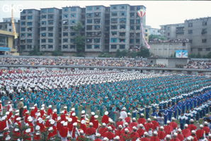 Grande fête pour célébrer le retour de Hong Kong à la Chine. Une foule à faire pâlir les commissions de sécurité les plus laxistes, les couleurs vives des costumes d'une multitude de figurants contrastent avec la grisaille des bâtiments alentours. Et le tout pour un spectacle de deux heures ou se côtoient le pire et le meilleur... Stade de Liupanshui (Suicheng, Guizhou)