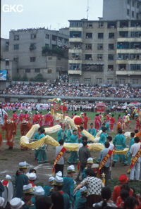 Grande fête pour célébrer le retour de Hong Kong à la Chine. Une foule à faire pâlir les commissions de sécurité les plus laxistes, les couleurs vives des costumes d'une multitude de figurants contrastent avec la grisaille des bâtiments alentours. Et le tout pour un spectacle de deux heures ou se côtoient le pire et le meilleur... Stade de Liupanshui (Suicheng, Guizhou)