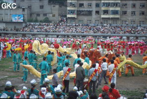 Grande fête pour célébrer le retour de Hong Kong à la Chine. Une foule à faire pâlir les commissions de sécurité les plus laxistes, les couleurs vives des costumes d'une multitude de figurants contrastent avec la grisaille des bâtiments alentours. Et le tout pour un spectacle de deux heures ou se côtoient le pire et le meilleur... Stade de Liupanshui (Suicheng, Guizhou)