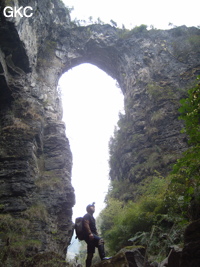 Li Ming Song devant le pont-naturel de Longqiaoge 龙桥阁 relique de l'ancienne galerie d'entrée de la grotte de Longqiaogedong (Grotte de la pagode de l'arche du dragon) 龙桥阁洞,  réseau de Longnudong 龙女洞. (Shipin, Zheng'an 正安, Zunyi Shi 遵义市, Guizhou 贵州省, Chine 中国)