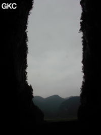 Dans le porche de Dadong 大洞 en contre-jour, se détachent les pitons qui bordent au sud-ouest le poljé de Rangshuiba.  (Wenquan, Suiyang 绥阳, Zunyi 遵义市, Guizhou 贵州省, Chine)