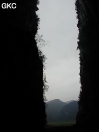 Dans le porche de Dadong 大洞 en contre-jour, se détachent les pitons qui bordent au sud-ouest le poljé de Rangshuiba.  (Wenquan, Suiyang 绥阳, Zunyi 遵义市, Guizhou 贵州省, Chine)