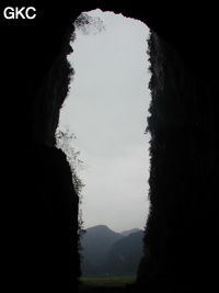 Dans le porche de Dadong 大洞 en contre-jour, se détachent les pitons qui bordent au sud-ouest le poljé de Rangshuiba.  (Wenquan,Suiyang 绥阳, Zunyi 遵义市, Guizhou 贵州省, Chine)