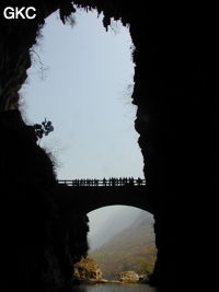 A contre-jour le porche d'entrée et le pont qui enjambe la puissante résurgence de la rivière Gesohe 革索出口. (Panxian, Liupanshui, Guizhou)