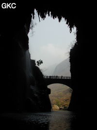 A contre-jour le porche d'entrée et le pont qui enjambe la puissante résurgence de la rivière Gesohe 革索出口. (Panxian, Liupanshui, Guizhou)