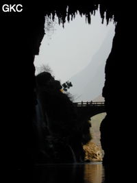 A contre-jour le porche d'entrée et le pont qui enjambe la puissante résurgence de la rivière Gesohe 革索出口. (Panxian, Liupanshui, Guizhou)